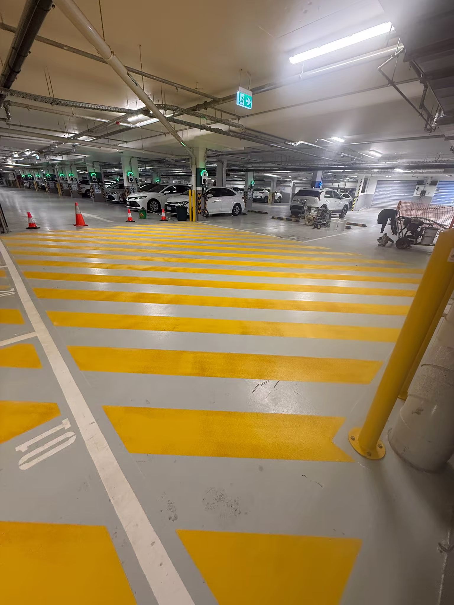 Crew equipment beside completed yellow floor hatching in an underground facility